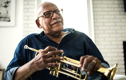 Older man smiling holding a Trumpet | Shared Health