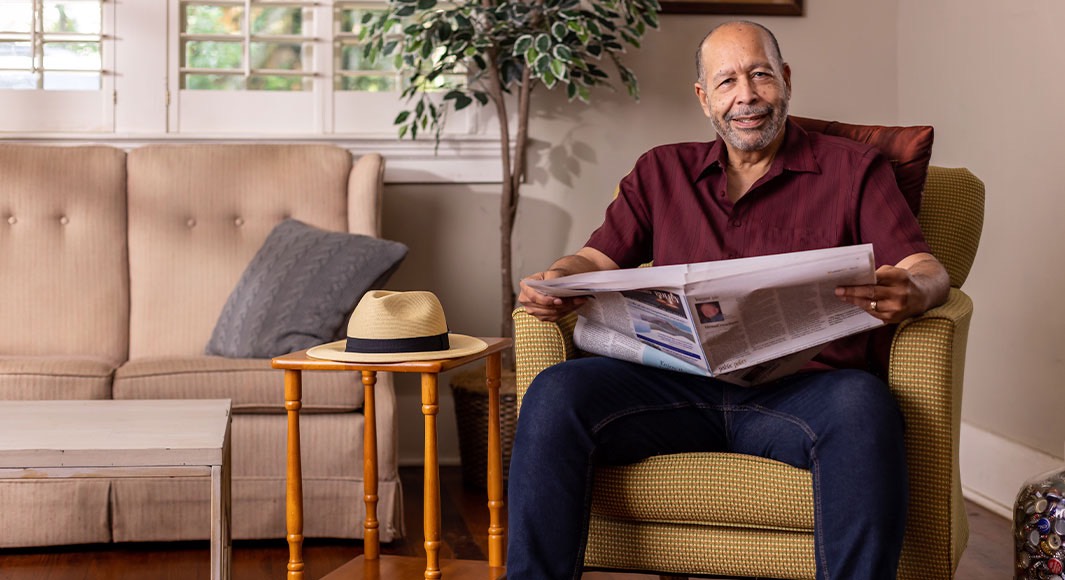 Older man sitting in a chair holding a newspaper